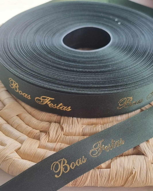 Fita decorativa verde-escura com letras douradas “Boas Festas” enrolada em rolo